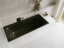 Schwarze Badewanne in hellem Bad mit weißen Fliesen, schwarzer Armatur, Vase mit Zweigen und Vorhang.