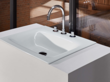 Стальная эмалированная раковина прямоугольной формы на белой встраиваемой панели с трехрычажным смесителем.