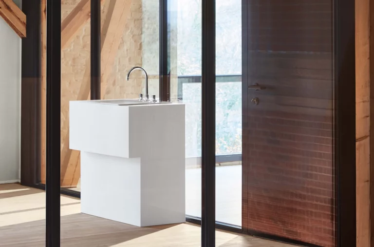 Современная прямоугольная раковина из стальной эмали на столешнице с смесителем в светлом помещении.