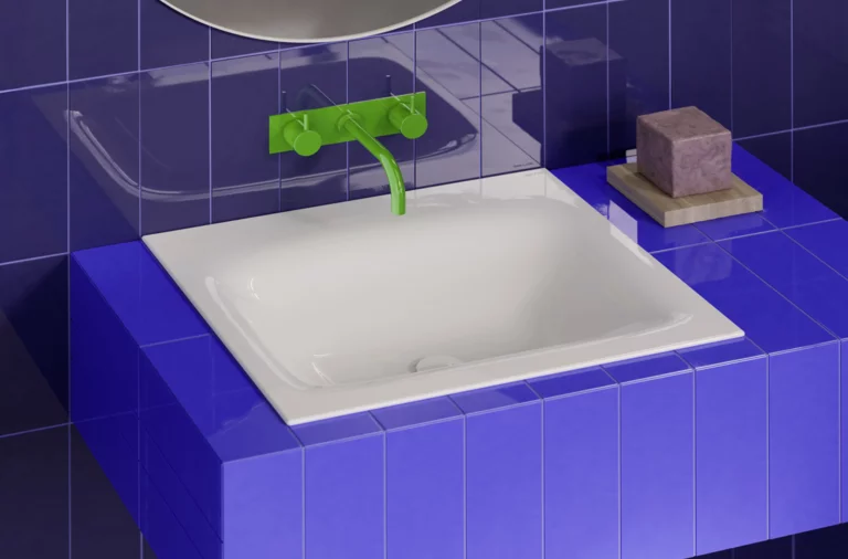 Weißes Waschbecken auf violett gefliestem Waschtisch, mit grüner Wandarmatur vor dunkelblauer Fliesenwand.