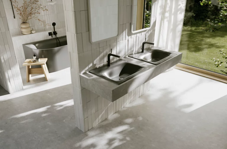 Helles Badezimmer mit zwei dunkelgrauen Waschtischen, schwarzen Armaturen, großer Fensterfront und Blick in den grünen Garten.