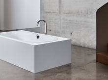 Freistehende rechteckige Badewanne aus Stahl-Email mit abgerundeter Innenform in modernem Badezimmer auf Betonboden.