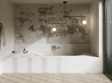 Cremefarbene Badewanne in hellem Bad mit Natursteinwand, Armatur, Pendelleuchten und großem Fenster.