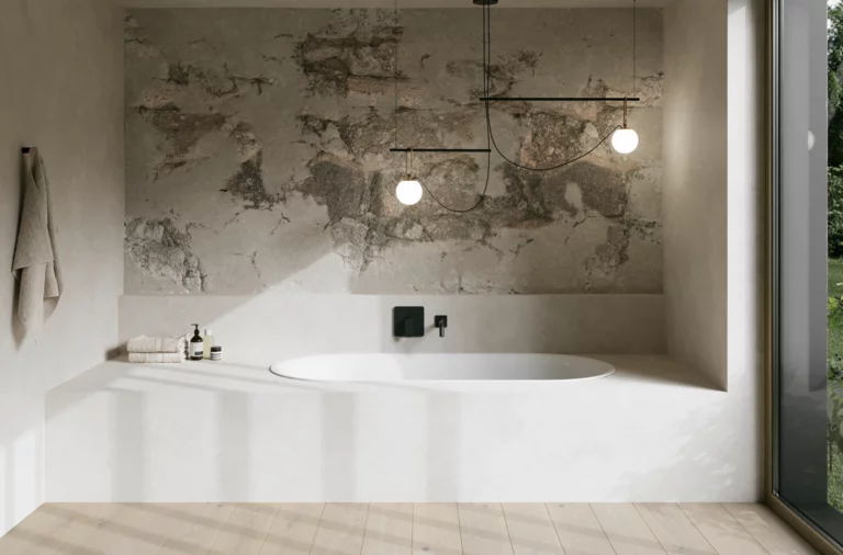 Weiße Badewanne in hellem Bad mit Steinoptik-Wand, schwarzer Armatur, Pendelleuchten und großem Fenster.