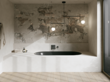 Schwarze Badewanne in hellem Bad mit Steinoptik-Wand, Armatur, Pendelleuchten und großem Fenster.