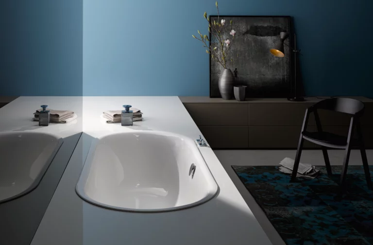 Weiße, ovale Badewanne aus Stahl-Email, in eine weiße Platte eingelassen, modernes Badezimmer mit Dekoration.