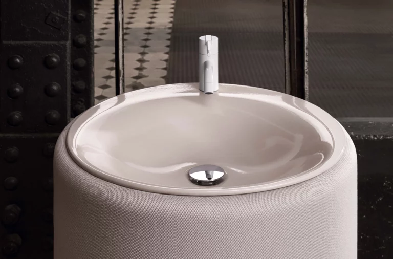 圆形搪瓷钢洗手盆安装在圆形台面上，现代水龙头，表面光亮，放在窗前。