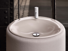 圆形搪瓷钢洗手盆安装在圆形台面上，现代水龙头，表面光亮，放在窗前。