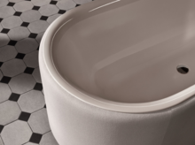Oval geformte Badewanne aus Stahl-Email auf gemustertem Fliesenboden.