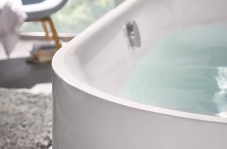 Bañera redonda de acero esmaltado llena de agua, primer plano del borde, ambiente de baño moderno.