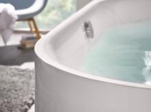 Bañera redonda de acero esmaltado llena de agua, primer plano del borde, ambiente de baño moderno.