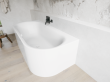 Weiße freistehende Badewanne vor heller Steinoptik-Wand mit schwarzer Armatur und Holzfußboden.