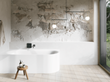 Weiße Badewanne in hellem Bad mit Steinoptik-Wand, schwarzer Armatur, Pendelleuchten und großem Fenster.
