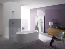 Vrijstaand ovaal bad van staal-email in moderne badkamer met paarse muur en minimalistisch design.
