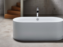 独立椭圆形钢搪瓷浴缸，带中间排水口，位于现代简约浴室内。