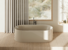 Freestanding oval bathtub in front of a large window with curtains; black floor-mounted faucet, warm daylight, minimalist spa look.