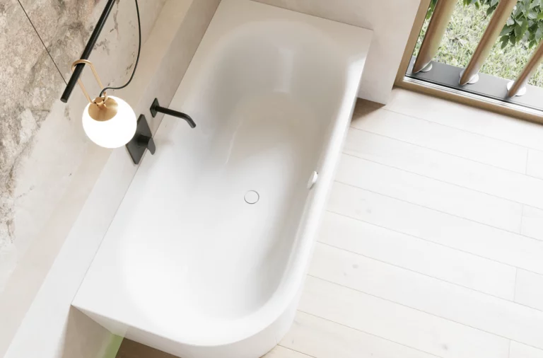 Helles Bad mit weißer freistehender Badewanne, schwarzer Armatur, Pendelleuchte und Fensterblick ins Grüne.