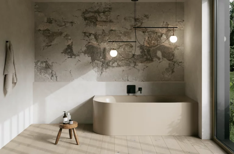 Modernes Bad mit beigefarbener freistehender Badewanne, Natursteinwand, Hocker und großen Fenstern.