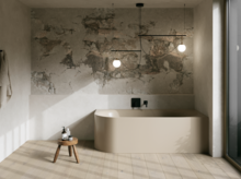 Modernes Bad mit beigefarbener freistehender Badewanne, Natursteinwand, Hocker und großen Fenstern.