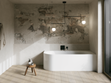 Modernes Bad mit weißer freistehender Badewanne, Natursteinwand, Hocker und großen Fenstern.