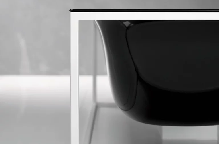 Black freestanding oval bathtub made of steel enamel, surrounded by white metal frame.