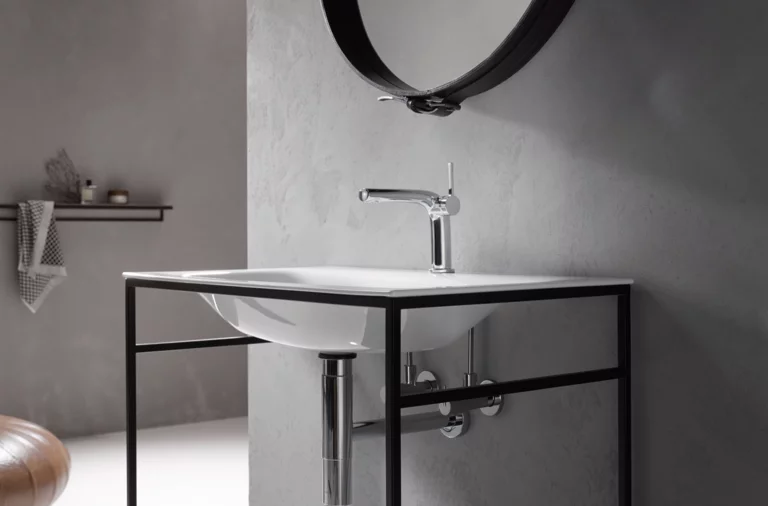 Rechteckiges Waschbecken aus Stahl-Email auf Einbauplatte mit Wasserhahn, schwarzes Gestell, Spiegel an der Wand.