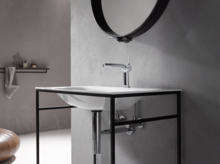 Rechteckiges Waschbecken aus Stahl-Email auf Einbauplatte mit Wasserhahn, schwarzes Gestell, Spiegel an der Wand.