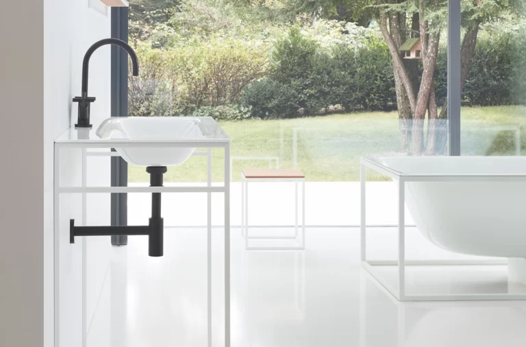 Rectangular bathtub and washbasin made of steel enamel, washbasin on square countertop in modern, bright bathroom.