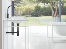 Rectangular bathtub and washbasin made of steel enamel, washbasin on square countertop in modern, bright bathroom.