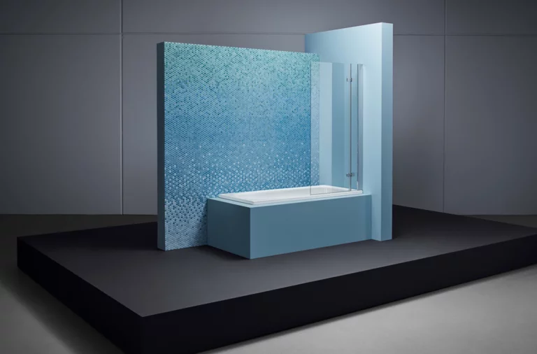 Rechteckige Badewanne aus Stahl-Email, teilweise umbaut, mit blauer Mosaikfliese und Glas-Duschabtrennung.