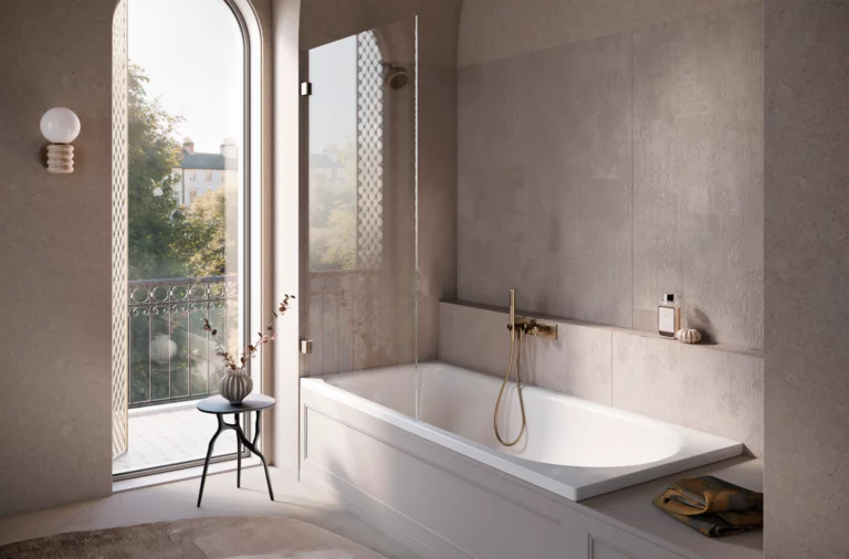 Salle de bains lumineuse avec baignoire-douche, paroi vitrée, robinet doré et vue sur balcon et arbres par haute fenêtre.