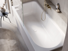 Moderne Dusch-Badewanne mit Glasabtrennung, goldener Armatur und seitlichem Fenster mit Blick auf Balkon und Fliesenboden.