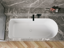 Weiße Badewanne in grauer Nische, von oben gesehen, mit schwarzer Armatur und hellem Fischgrätboden.