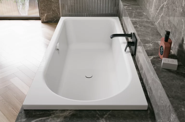 Weiße Badewanne in grauer Badezimmernische mit schwarzer Armatur und heller Holzoptik im Raum.