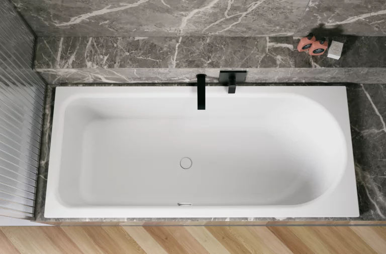 Weiße Badewanne in grauer Nische, von oben gesehen, mit schwarzer Armatur und hellem Fischgrätboden.