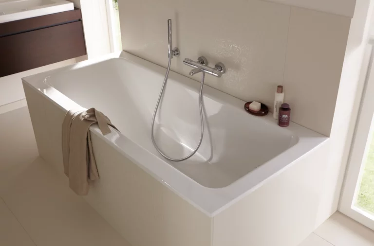 Rechteckige, weiße Badewanne aus Stahl-Email mit Handbrause, eingebaut in eine helle Badezimmerumgebung.