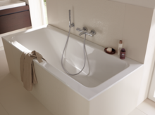 Rechteckige, weiße Badewanne aus Stahl-Email mit Handbrause, eingebaut in eine helle Badezimmerumgebung.