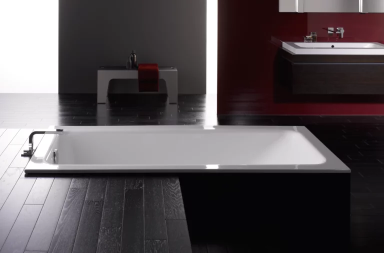 Rechteckige Badewanne aus Stahl-Email und rechteckiges Waschbecken auf Einbauplatte in modernem Badezimmer.