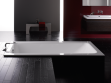 Baignoire rectangulaire en acier émaillé et lavabo rectangulaire sur plan de travail dans salle de bains moderne.