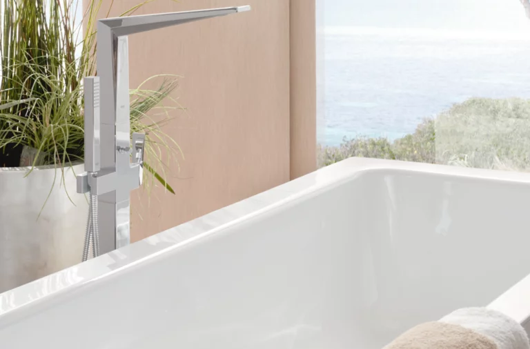 Rechteckige Badewanne aus Stahl-Email mit moderner Armatur, im Vordergrund Handtuch, im Hintergrund Pflanzen und Fenster.