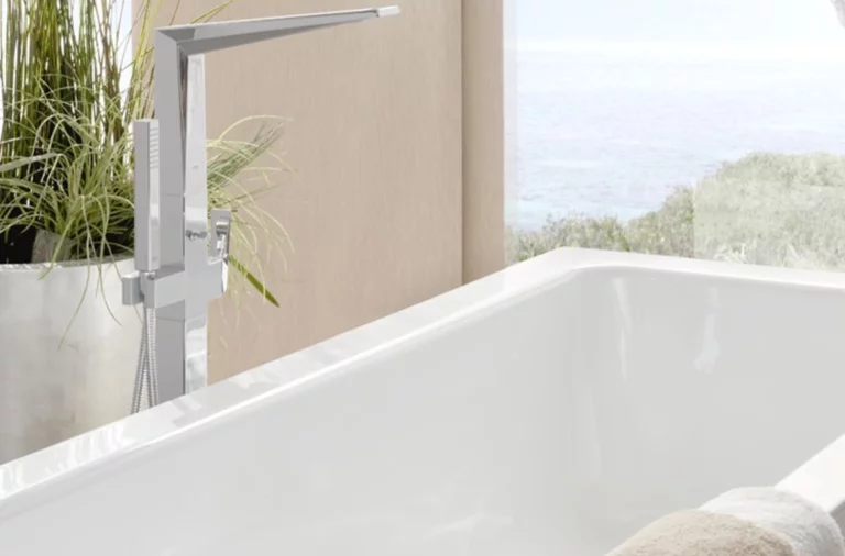 Baignoire rectangulaire en acier émaillé avec robinetterie moderne, serviette au premier plan, plantes et fenêtre à l’arrière-plan.