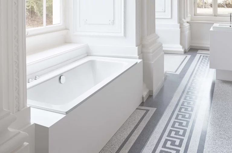 Rechteckige Badewanne aus Stahl-Email und rechteckiges Waschbecken auf Einbauplatte in hellem, klassischem Badezimmer.