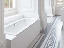 Rechteckige Badewanne aus Stahl-Email und rechteckiges Waschbecken auf Einbauplatte in hellem, klassischem Badezimmer.