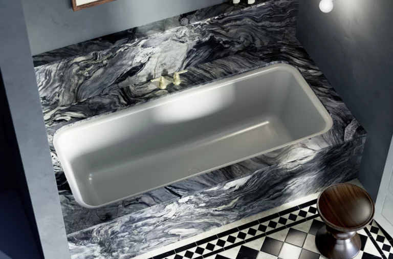 Eingelassene Badewanne mit auffälliger Marmorverkleidung in Blau-Schwarz-Tönen und klassisch gemustertem Fliesenboden.
