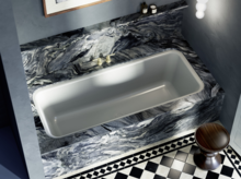 Baignoire encastrée avec habillage marbré bleu-noir saisissant et sol en carreaux à motifs classiques.