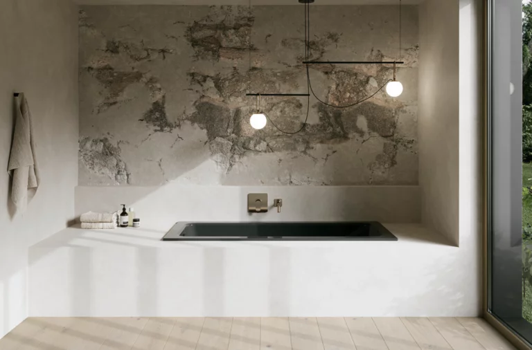 Dunkle Badewanne in heller Nische mit Natursteinoptik, Wandarmatur und großen Fenstern.