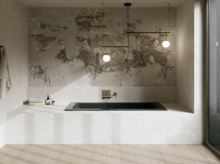 Dunkle Badewanne in heller Nische mit Natursteinoptik, Wandarmatur und großen Fenstern.