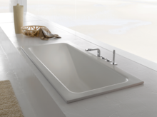 Rechteckige Stahl-Email-Badewanne, in weiße Fläche eingelassen, mit moderner Armatur und minimalistischem Design.