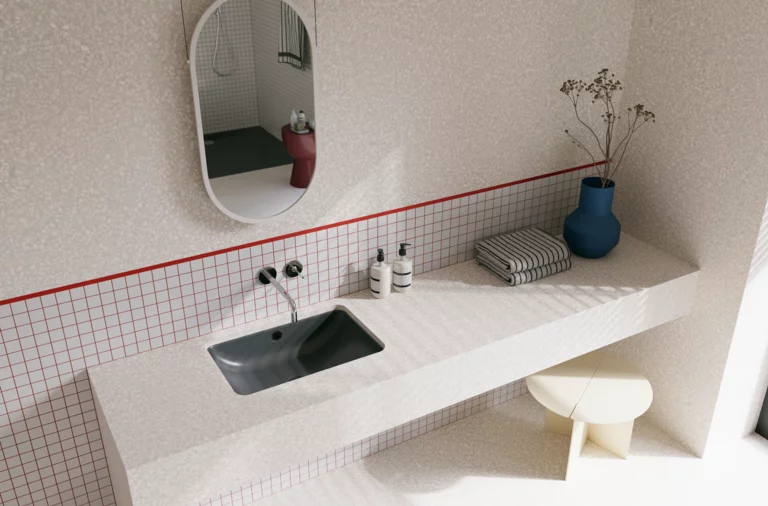 Helles Badezimmer mit dunkelgrauem Waschtisch, silberfarbenen Wandarmaturen, ovalem Spiegel, blauer Vase und gefliester Ablage.