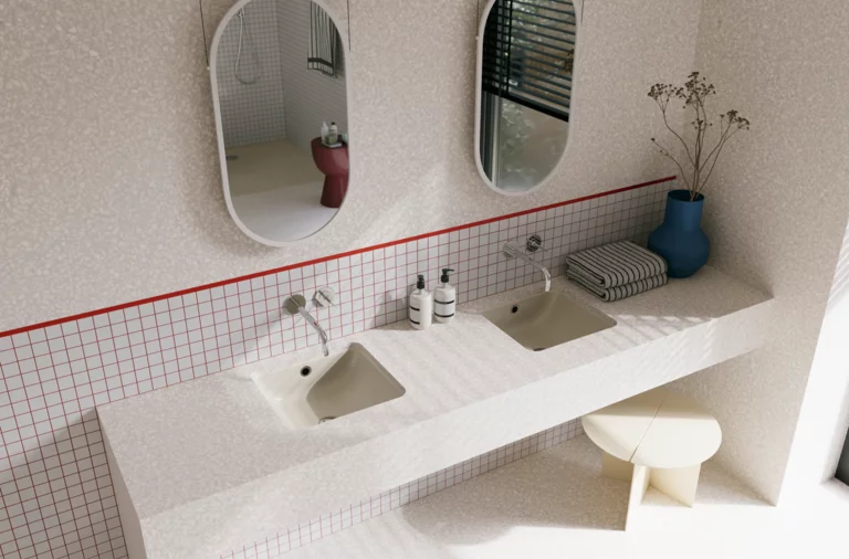 Helles Badezimmer mit zwei beigen Waschtischen, silberfarbenen Wandarmaturen, zwei ovalen Spiegeln und blauer Vase.